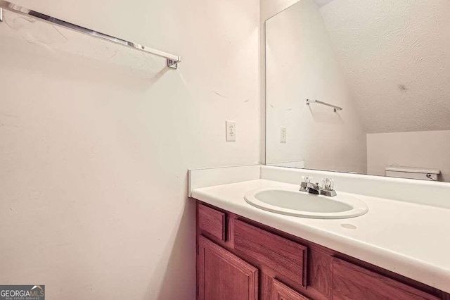 bathroom with vanity, toilet, and vaulted ceiling