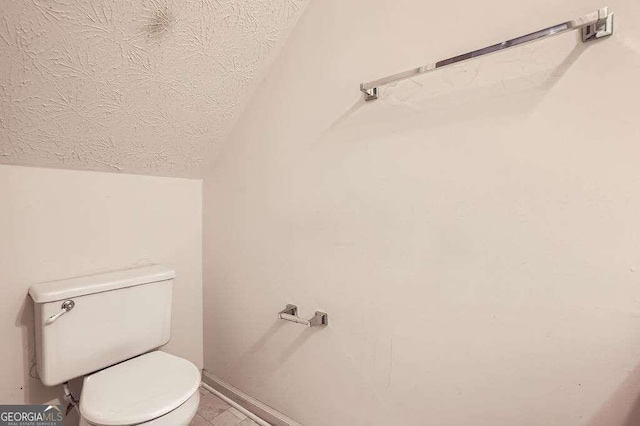 bathroom featuring toilet, a textured ceiling, and vaulted ceiling