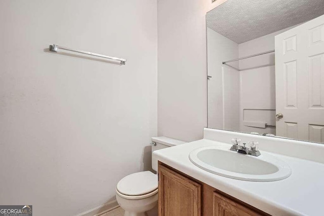 bathroom featuring vanity, a shower, a textured ceiling, and toilet