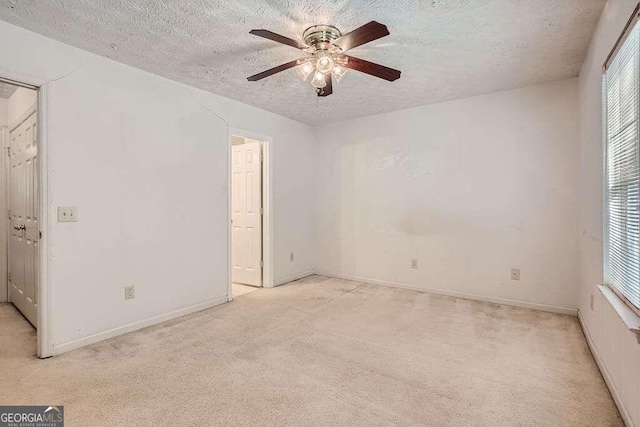 empty room with light carpet, ceiling fan, a textured ceiling, and plenty of natural light