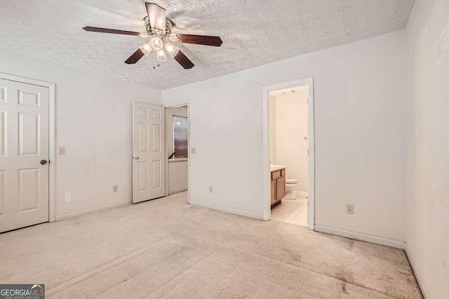 unfurnished bedroom featuring light carpet, a textured ceiling, ensuite bath, and ceiling fan