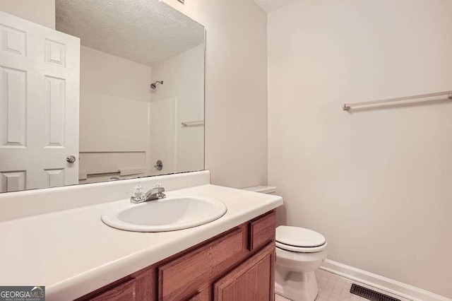 bathroom with tile patterned floors, toilet, vanity, a textured ceiling, and walk in shower