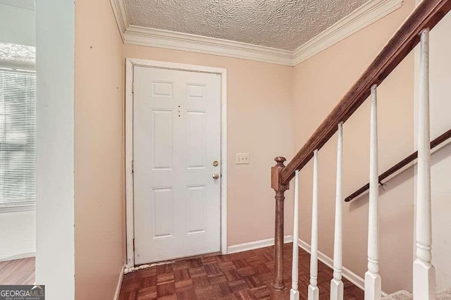 foyer entrance featuring a textured ceiling, ornamental molding, and dark parquet flooring