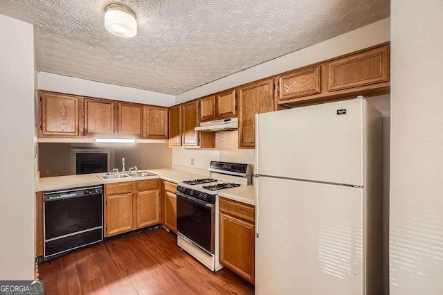 kitchen with white appliances, dark wood-type flooring, a textured ceiling, and sink