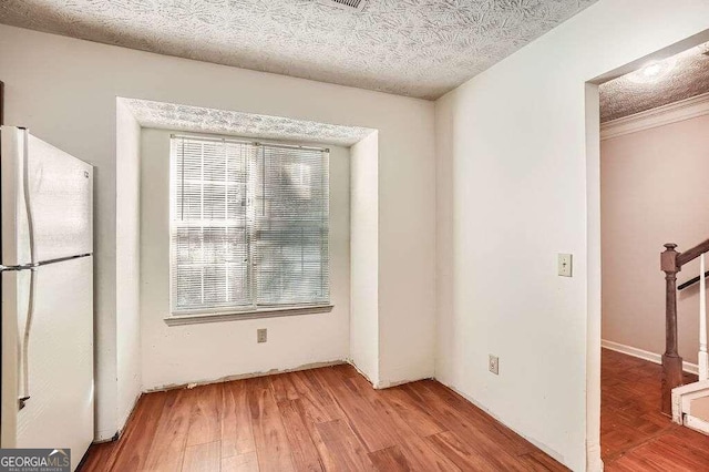 unfurnished dining area featuring wood-type flooring and a textured ceiling