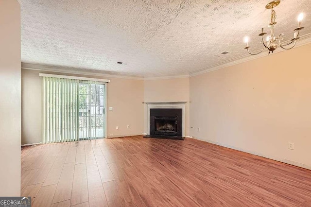 unfurnished living room featuring a textured ceiling, ornamental molding, a chandelier, and hardwood / wood-style floors