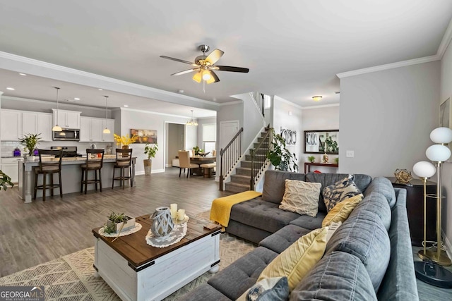 living room with crown molding, wood-type flooring, and ceiling fan