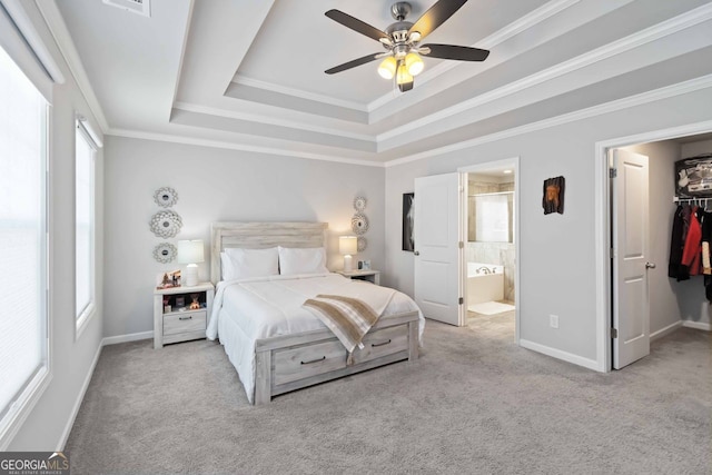 bedroom with connected bathroom, a tray ceiling, a spacious closet, light colored carpet, and ceiling fan