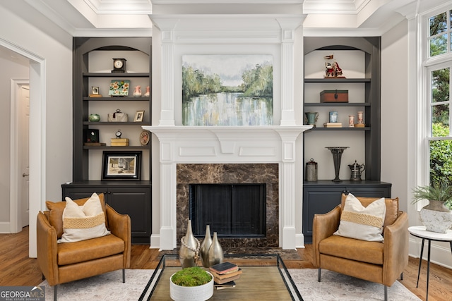 living area with built in features, a fireplace, and hardwood / wood-style floors