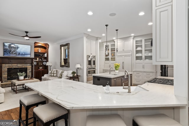 kitchen with sink, paneled built in refrigerator, kitchen peninsula, and decorative light fixtures