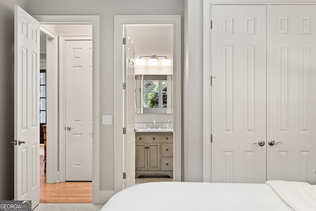 bedroom with sink, light hardwood / wood-style flooring, and ensuite bathroom