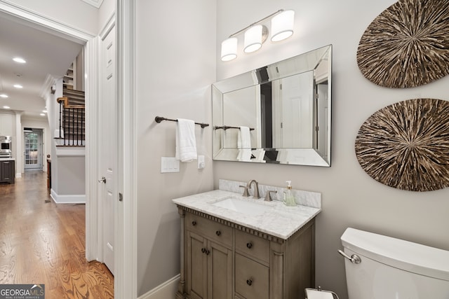 bathroom with toilet, hardwood / wood-style flooring, and vanity