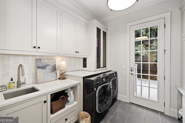 washroom with dark tile patterned flooring, sink, washing machine and clothes dryer, crown molding, and cabinets