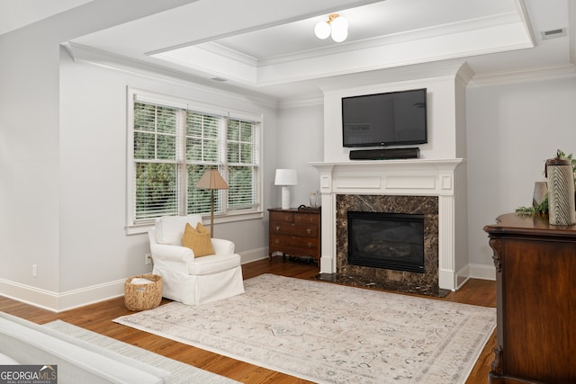 living area with crown molding, a premium fireplace, and dark hardwood / wood-style floors