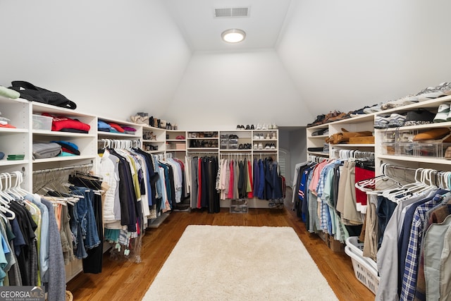 spacious closet with vaulted ceiling and dark hardwood / wood-style flooring