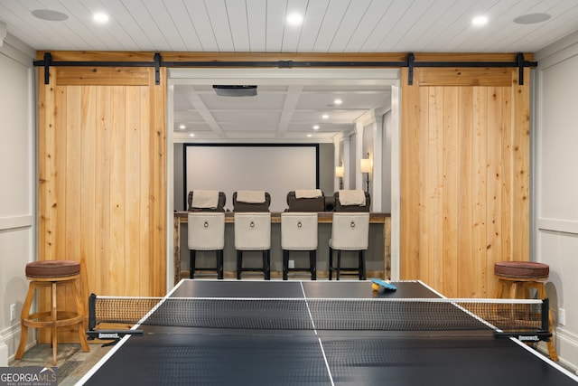 recreation room featuring wooden walls and a barn door