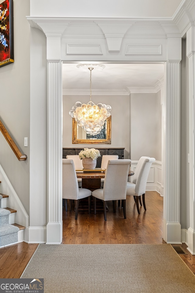 dining space featuring ornamental molding, hardwood / wood-style flooring, a chandelier, and ornate columns