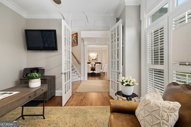 interior space featuring french doors, hardwood / wood-style flooring, ornamental molding, and an inviting chandelier