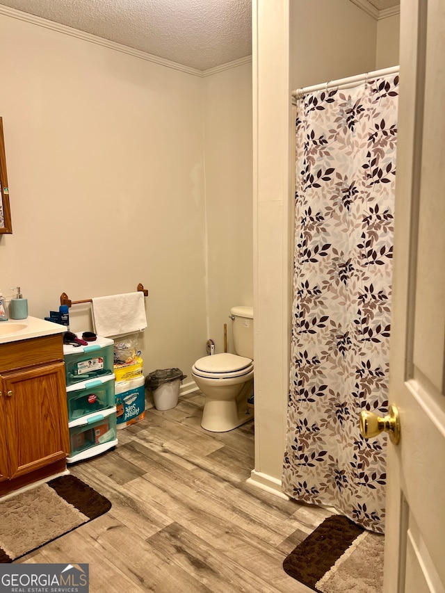 bathroom with toilet, ornamental molding, hardwood / wood-style floors, vanity, and a textured ceiling