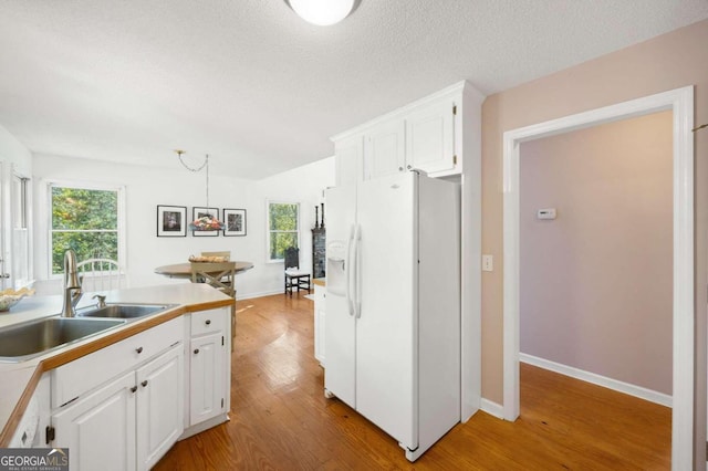 kitchen with plenty of natural light, white cabinetry, and white fridge with ice dispenser