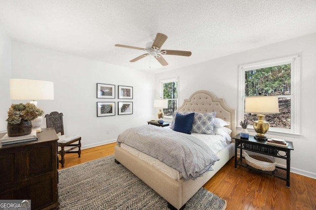 bedroom featuring ceiling fan, wood-type flooring, and a textured ceiling