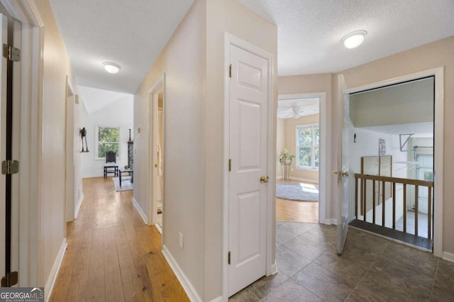 corridor featuring a textured ceiling and dark hardwood / wood-style flooring