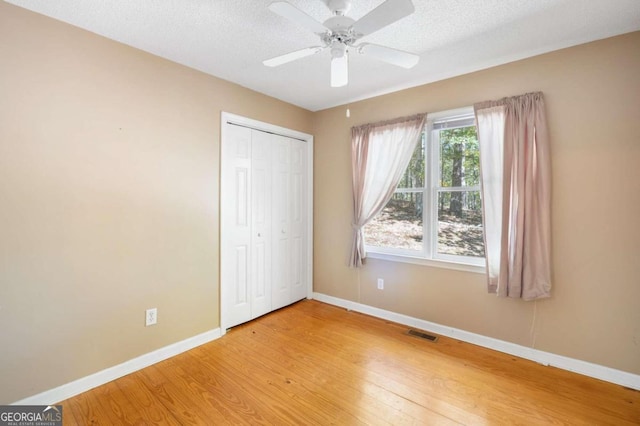 unfurnished bedroom featuring a closet, ceiling fan, a textured ceiling, and light hardwood / wood-style flooring