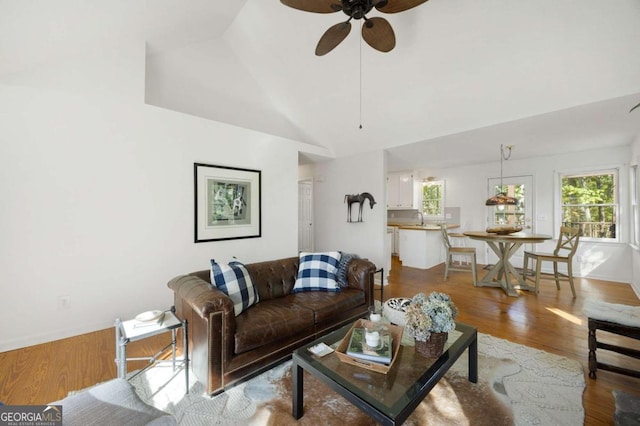 living room featuring light hardwood / wood-style flooring, sink, high vaulted ceiling, and ceiling fan