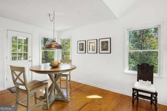 dining space with lofted ceiling, wood-type flooring, and a healthy amount of sunlight