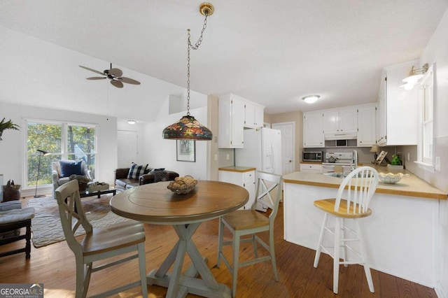 dining room featuring ceiling fan, vaulted ceiling, and dark hardwood / wood-style flooring