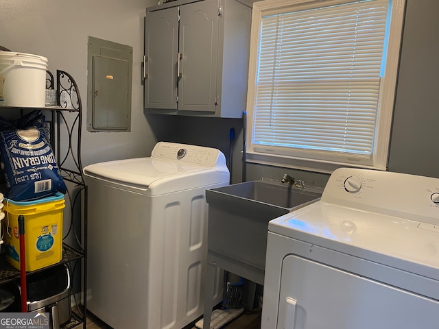 laundry room featuring electric panel, washing machine and dryer, and cabinets