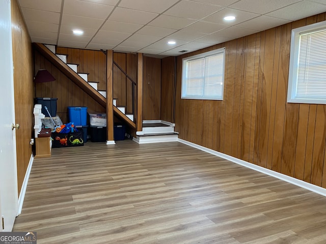 basement featuring wood walls, plenty of natural light, and light wood-type flooring