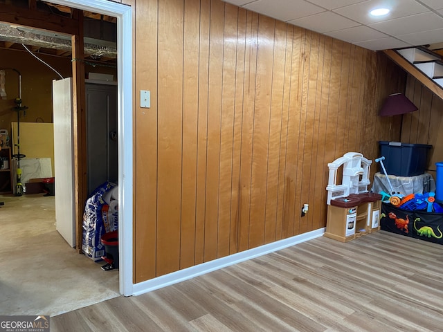 interior space with light hardwood / wood-style floors, wood walls, and a paneled ceiling