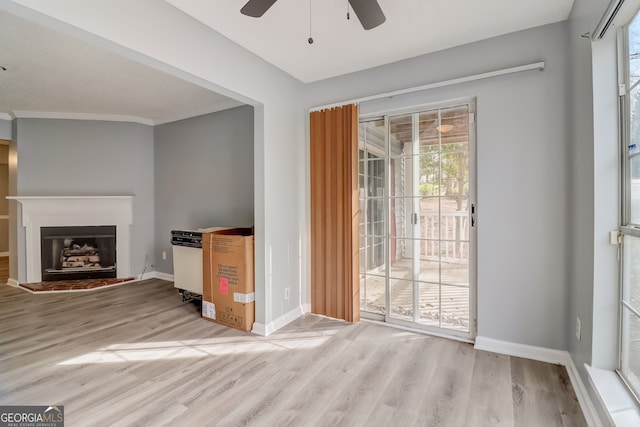 unfurnished living room with light hardwood / wood-style flooring, ornamental molding, and ceiling fan