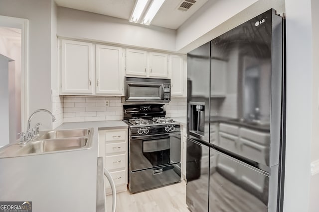 kitchen featuring decorative backsplash, white cabinetry, black appliances, light hardwood / wood-style floors, and sink