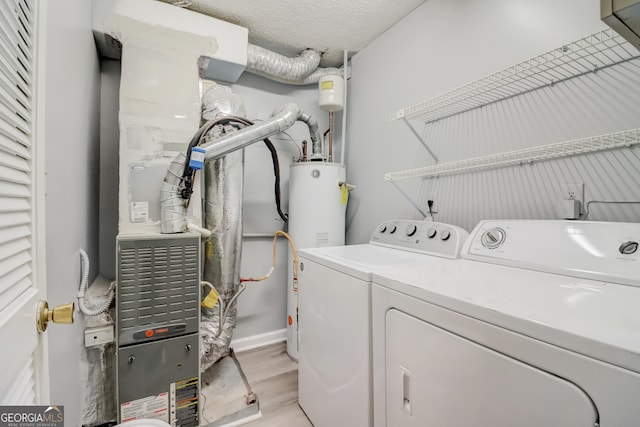 washroom featuring light hardwood / wood-style floors, washing machine and dryer, a textured ceiling, and gas water heater