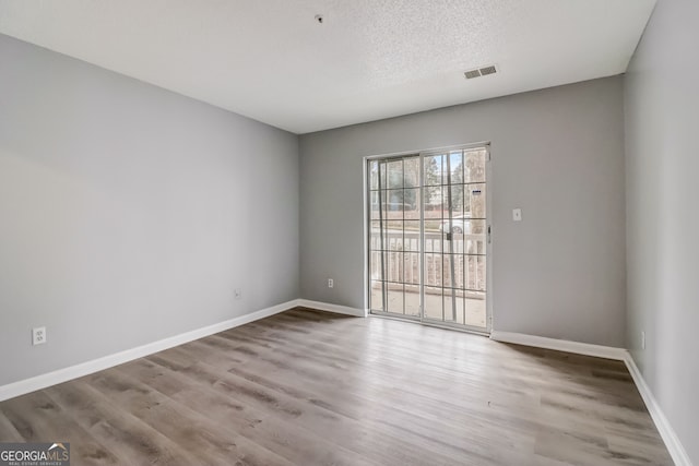 empty room with a textured ceiling and hardwood / wood-style flooring