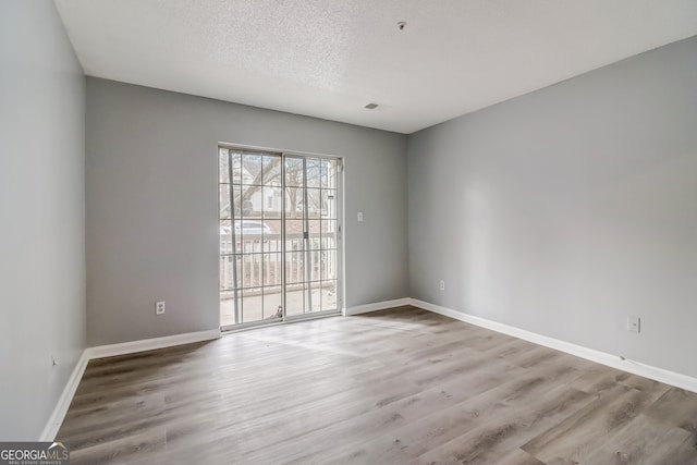 unfurnished room with hardwood / wood-style flooring and a textured ceiling