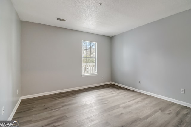 spare room with a textured ceiling and light wood-type flooring