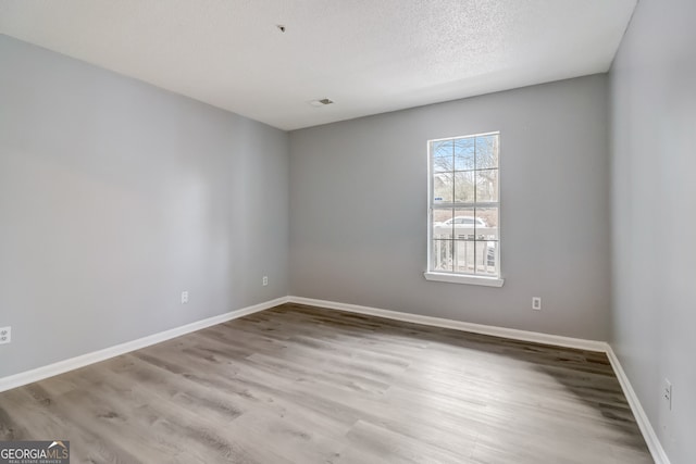 unfurnished room with a textured ceiling and light hardwood / wood-style flooring