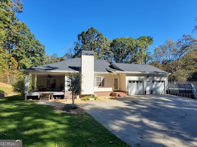 rear view of house with a yard, a garage, and ceiling fan