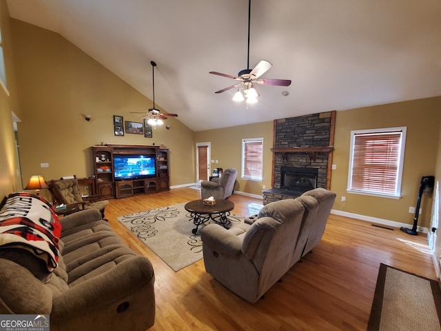 living room with light hardwood / wood-style floors, high vaulted ceiling, a fireplace, and ceiling fan