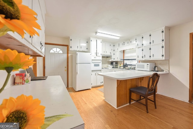 kitchen with white appliances, white cabinetry, and kitchen peninsula