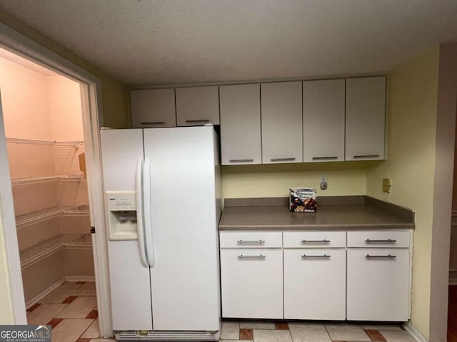 kitchen with a textured ceiling and white refrigerator with ice dispenser