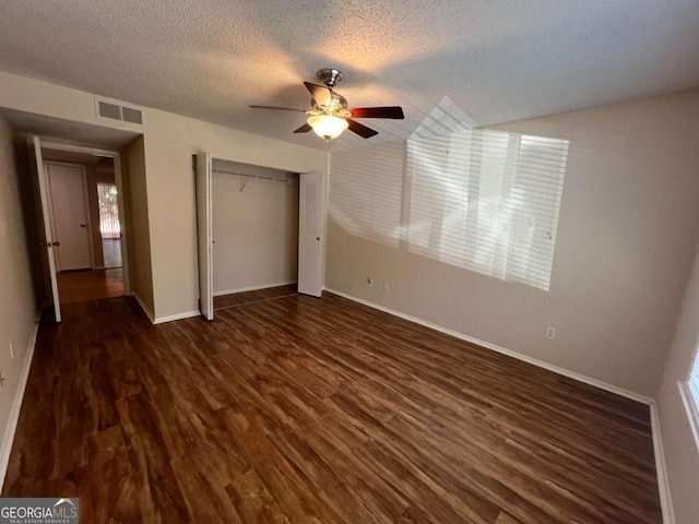 unfurnished bedroom featuring a closet, dark hardwood / wood-style floors, a textured ceiling, and ceiling fan