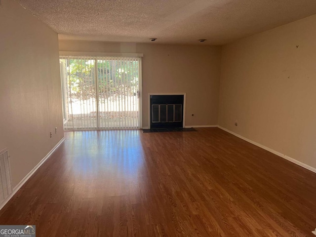 spare room with a textured ceiling and dark hardwood / wood-style floors