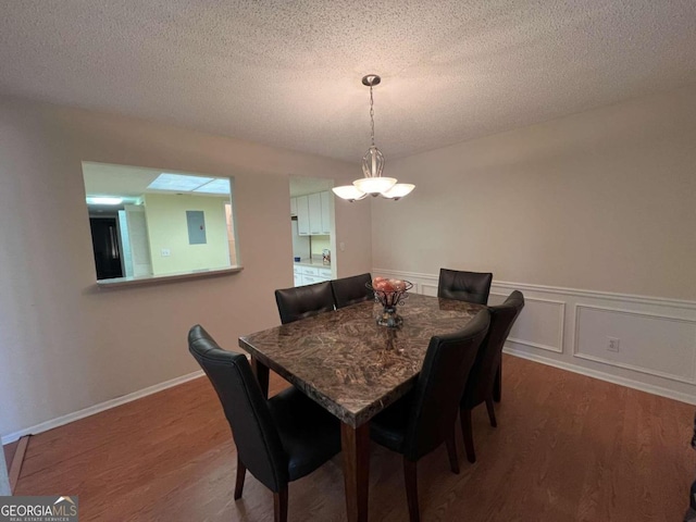 dining area featuring a textured ceiling, electric panel, and hardwood / wood-style flooring