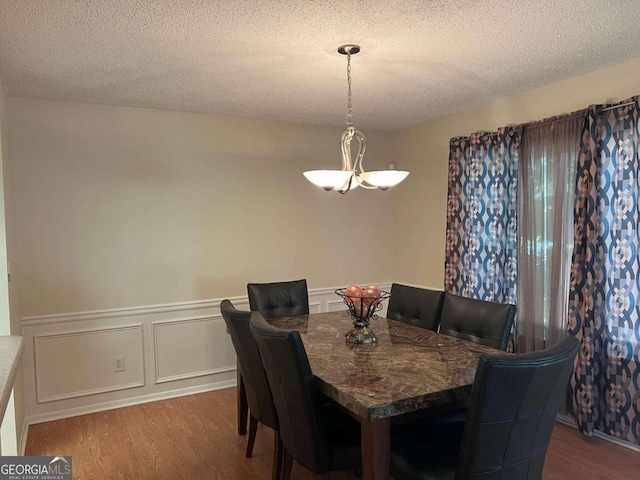 dining area with a textured ceiling and wood-type flooring