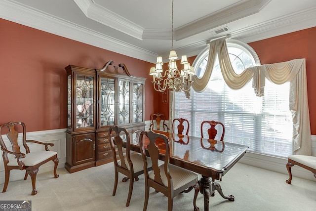 dining space with light colored carpet, ornamental molding, a notable chandelier, and a raised ceiling