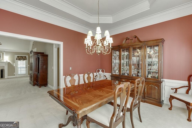 dining space with ornamental molding, an inviting chandelier, a raised ceiling, and light colored carpet